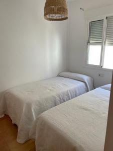 two beds in a white room with a window at casa en Islantilla in Isla Cristina