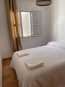 a bedroom with a white bed with two towels on it at casa en Islantilla in Isla Cristina