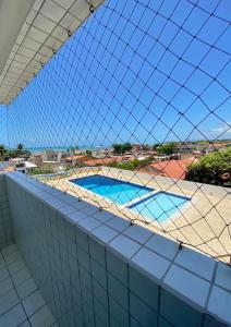 Blick auf einen Swimmingpool durch einen Zaun in der Unterkunft PROMOÇÃO INAUGURAÇÃO - Apto Melhor localização in São José da Coroa Grande
