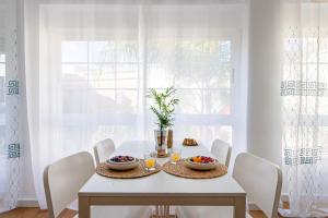 a white dining room with a white table and chairs at UNIQUE Plaza Higuitos in Almuñécar +16 photos