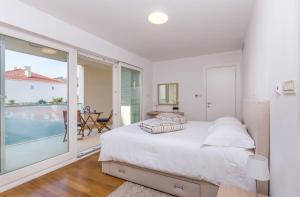 a white bedroom with a bed and a balcony at Dubrovnik Luxury Residence – L’Orangerie in Dubrovnik