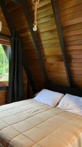 a bed in a room with a wooden ceiling at Oasis Chalés Camboriú in Camboriú