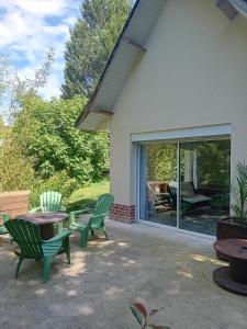 a patio with green chairs and a table at Le Murmure de la petite Oasis in Neslette