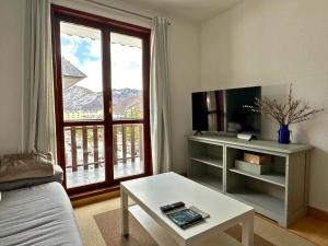 a living room with a couch and a table and a window at Cervino 2 Apartamento en Formigal Pueblo in Formigal