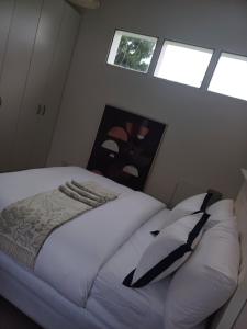 a bedroom with a white bed with pillows and windows at Chuu's Cosy Place in East London