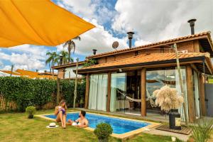 un groupe de personnes assises autour d'une piscine dans une maison dans l'établissement Sítio da Montanha, à Piedade