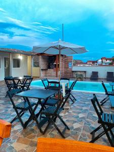 a table and chairs with an umbrella next to a pool at Pousada Sinhá Moça in Diamantina