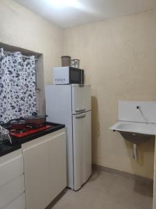 a kitchen with a white refrigerator and a sink at Studio mobiliado 3 in Contagem