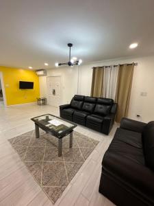 a living room with a black couch and a table at Gentlemen's Suite - 3 Bedroom in Beterverwagting