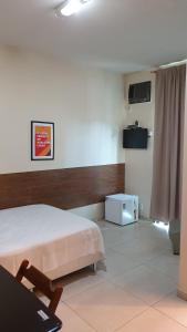 a bedroom with a bed and a table and a tv at Hotel Muriaé in Muriaé