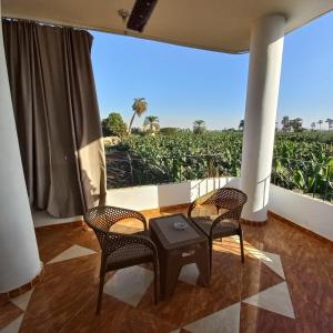 a room with two chairs and a table and a large window at Banana Guest House in Luxor
