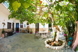 a patio with a tree and tables and chairs at Studios Ifigenia in Skala Potamias