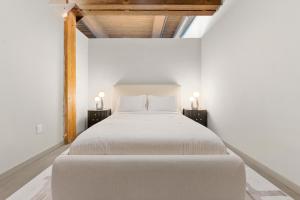 ジャージー・シティーにあるThe Aurelia - Luxury Industrial Loft near NYCの白いベッドと2つのナイトスタンドを備えた寝室