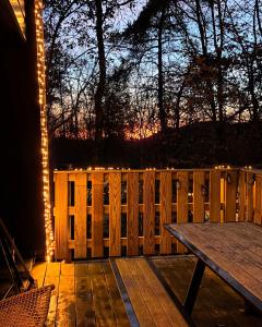 a wooden deck with a table and a fence with lights at Boshuisje Durbuy Nr6 in Durbuy