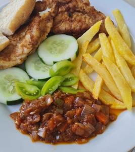 a plate of food with meat and french fries at Flamingo Beach in Sanyang
