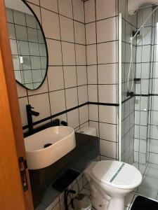 a bathroom with a sink and a toilet and a mirror at Kit 102 Brasília in Brasilia