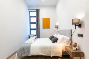 Un dormitorio blanco con una cama y una silla. en New and spacious loft area Numancia, en Madrid