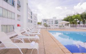a row of white chairs next to a swimming pool at Premier Residence Hotel em Brasília 21604 in Brasilia