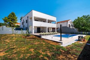 a white house with a swimming pool in front of it at Apartment ILUX-3 in Novigrad Dalmatia