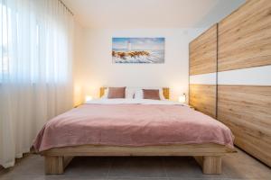 a bedroom with a large bed with a wooden headboard at Apartment ILUX-3 in Novigrad Dalmatia +16 photos
