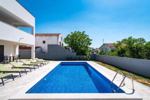 a swimming pool with lounge chairs next to a house at Apartment ILUX-3 in Novigrad Dalmatia