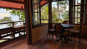 a porch with a table and chairs and windows at Glamping Sitio das Tartarugas in Praia da Longa