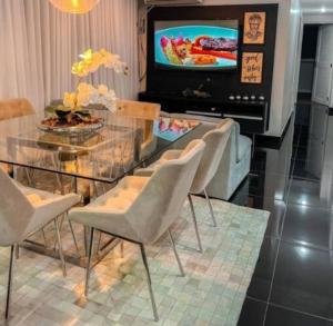 a dining room with a glass table and chairs and a television at Apto próximo ao Shopping Boulevard in Belém