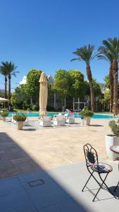 a patio with chairs and a pool with palm trees at Royal Park Eilat 138 duplex in Eilat