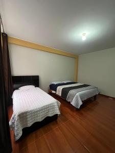 two beds in a room with wooden floors at 3era Habitación Privada a 1 cuadra de la plaza de armas in Oxapampa