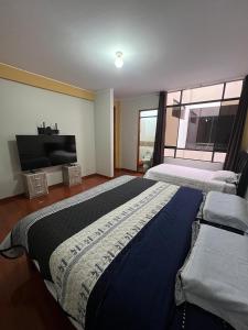 a bedroom with two beds and a flat screen tv at 3era Habitación Privada a 1 cuadra de la plaza de armas in Oxapampa