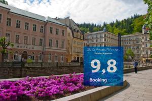 um sinal no meio de uma cidade com flores roxas em Pension Napoleon em Karlovy Vary