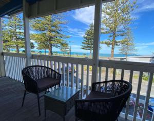 two chairs and a table on a porch with a view of the beach at Bluewater Lodge in Napier