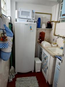 a small kitchen with a microwave on top of a refrigerator at Apt centro in Poços de Caldas