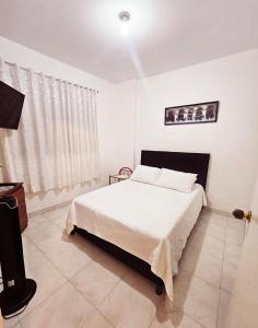 a white bedroom with a bed and a window at Villa Claudia - apartamento cómodo y tranquilo in El Colegio