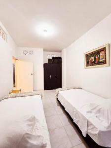 a bedroom with two beds and a black cabinet at Villa Claudia - apartamento cómodo y tranquilo in El Colegio