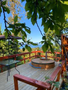 a wooden deck with a bench and a tree at Cabaña entre mares Huelmo in Puerto Montt +45 photos