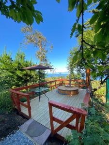 a wooden deck with two benches and an umbrella at Cabaña entre mares Huelmo in Puerto Montt