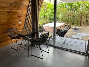 a glass table and chairs on a patio with a tub at IkI Tiny Villa in Fortuna