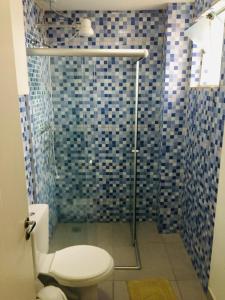 uma casa de banho com um WC e um chuveiro com azulejos azuis em Hotel Santos Reis em Aparecida