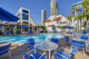 a swimming pool with blue chairs and tables and a building at Downtown San Diego Condo 1 Mi to Gaslamp Quarter in San Diego