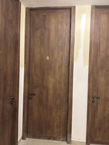 two wooden doors in a room with a wall at فلج هزاع in Al Muwayqi‘ī