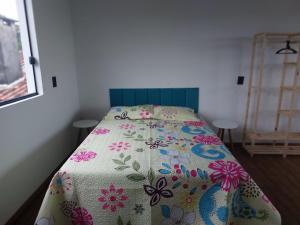 a small bedroom with a bed with a floral bedspread at Casa da Paz -Praia do Rosa in Imbituba