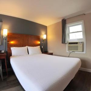 ein Schlafzimmer mit einem großen weißen Bett und einem Fenster in der Unterkunft Moonlight Inn and Suites Sudbury in Sudbury