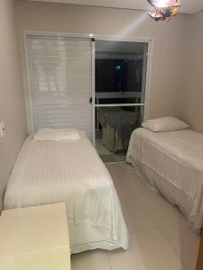 a bedroom with two beds and a sliding glass door at Riviera de Sao Lourenço mod08 in Bertioga +27 photos