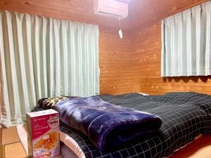 南小国町Whole house rental 天然温泉付きコテージRAI駐車場付き黒川温泉街まで車で5分的一间卧室，床上铺着一条蓝色的毯子