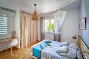 a bedroom with a bed and a desk and a window at Villa Les Saintes 4/5 p à 50m de la plage de l'anse de Mancillier in Saint-François