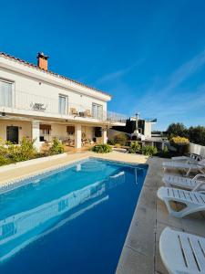 a swimming pool in front of a house with chairs at Exclusiva casa con vistas despejadas al mar y piscina privada in Lloret de Mar
