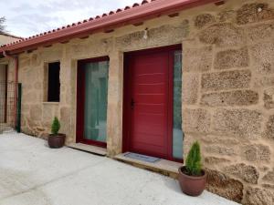 a red door on a brick house with two potted plants at Casa da Ramona in Ribadavia