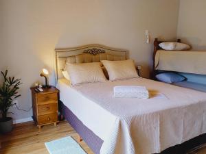 a bedroom with a bed with white sheets and a night stand at Chalés do Pedro Hospedagem e Restaurante in Praia de Araçatiba