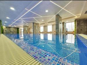 a large swimming pool with blue tiles on the floor at Green Apartment&Spa in Zlatibor